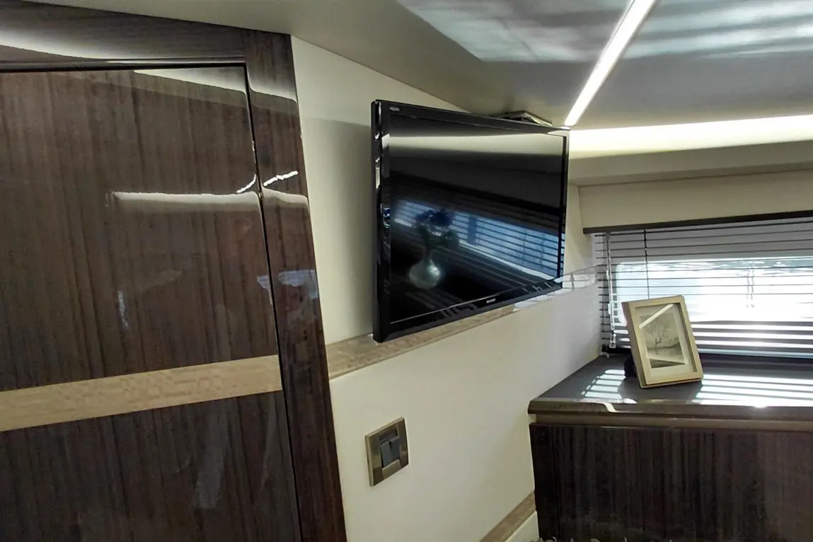 Modern interior featuring a wall-mounted TV, stylish cabinetry, and natural light through window blinds.